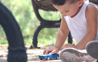 Child playing with toy car in a park