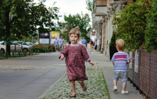 Two young children walking in a city