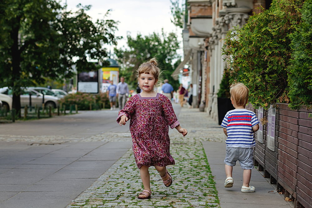 Two young children walking in a city